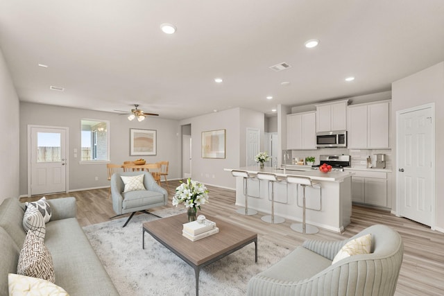 living room featuring recessed lighting, a ceiling fan, baseboards, visible vents, and light wood-style floors