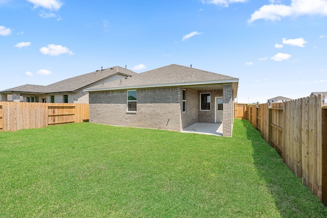 back of house featuring brick siding, a shingled roof, a lawn, a patio area, and a fenced backyard