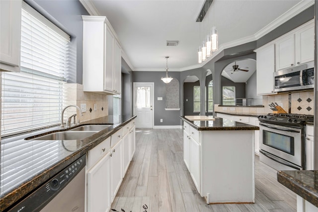 kitchen featuring hanging light fixtures, dark stone countertops, appliances with stainless steel finishes, and white cabinetry