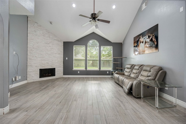 unfurnished living room with light wood-type flooring, high vaulted ceiling, a fireplace, and ceiling fan