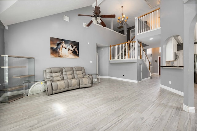 living room with ceiling fan with notable chandelier, high vaulted ceiling, and light hardwood / wood-style floors