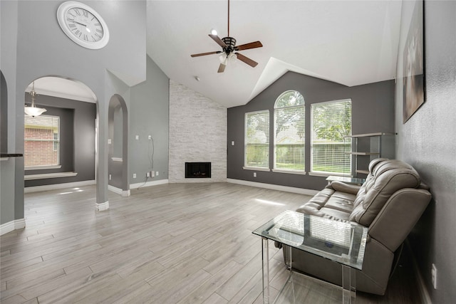 living room with high vaulted ceiling, ceiling fan, a fireplace, and light hardwood / wood-style flooring