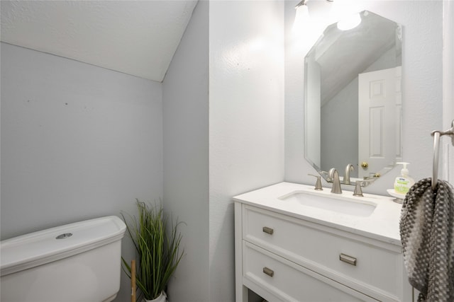 bathroom featuring vanity, toilet, and vaulted ceiling