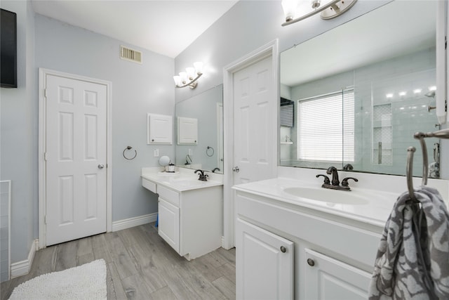 bathroom with a shower with door, vanity, and wood-type flooring