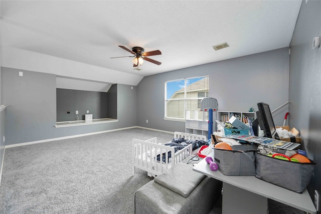 interior space with lofted ceiling, ceiling fan, carpet, and a textured ceiling