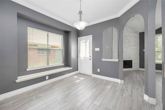 entryway with a fireplace, ornamental molding, and light hardwood / wood-style flooring