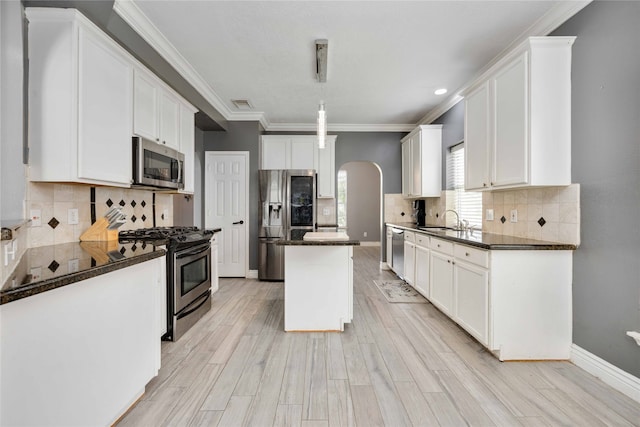 kitchen with light wood-type flooring, white cabinetry, stainless steel appliances, a kitchen island, and sink