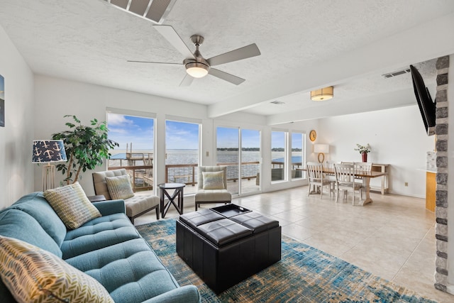 living room with a textured ceiling, ceiling fan, and tile patterned flooring