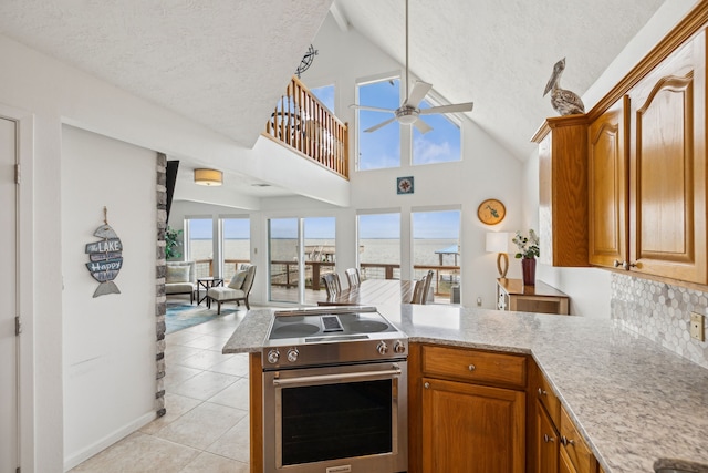 kitchen with electric stove, a textured ceiling, light tile patterned floors, kitchen peninsula, and ceiling fan