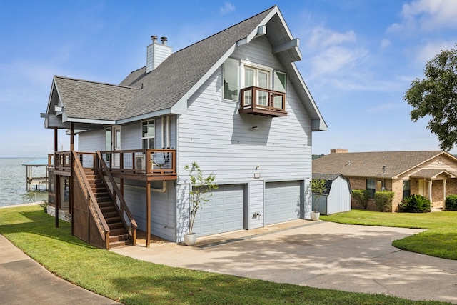 view of front facade with a garage, a front yard, and a water view