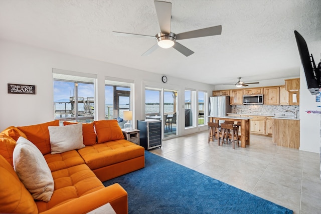 living room featuring a wealth of natural light, ceiling fan, a textured ceiling, and light tile patterned flooring