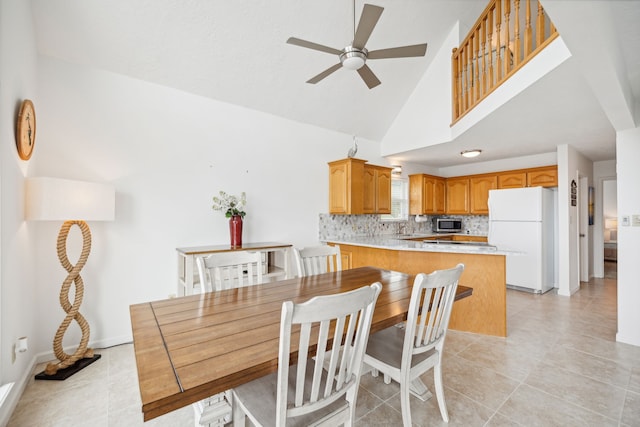 dining space with ceiling fan, sink, light tile patterned floors, and high vaulted ceiling