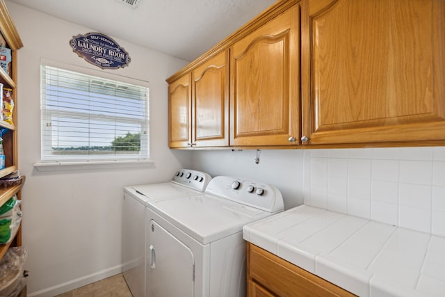 laundry room with cabinets, washer and clothes dryer, and tile patterned floors