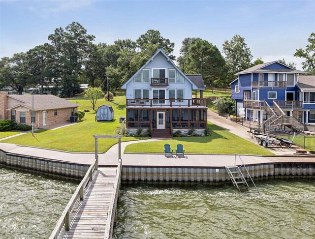 rear view of property featuring a lawn, a deck with water view, and a balcony