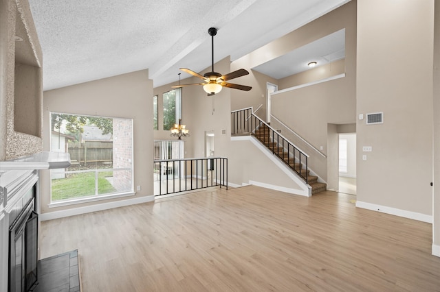 unfurnished living room featuring ceiling fan with notable chandelier, a textured ceiling, light hardwood / wood-style flooring, and high vaulted ceiling