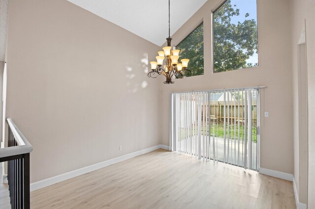 interior space with high vaulted ceiling, a notable chandelier, and hardwood / wood-style floors