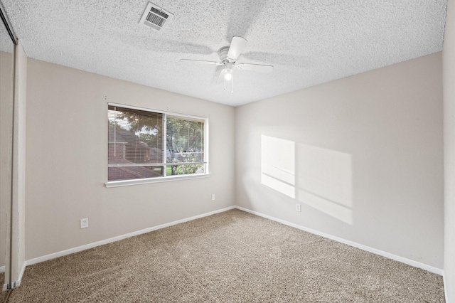 carpeted spare room featuring a textured ceiling and ceiling fan