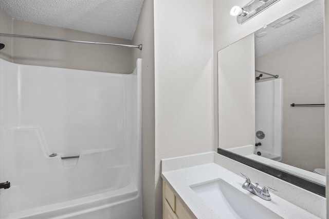 bathroom with a textured ceiling, vanity, and shower / washtub combination