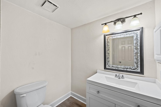 bathroom with toilet, vanity, wood-type flooring, and a textured ceiling