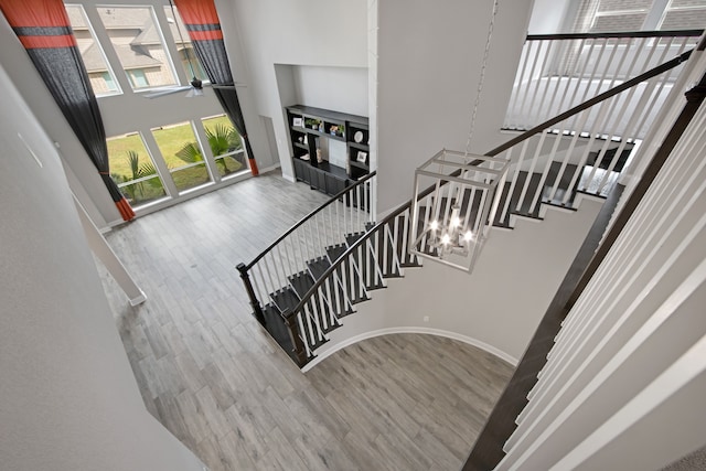 stairs featuring hardwood / wood-style flooring, ceiling fan, and a high ceiling