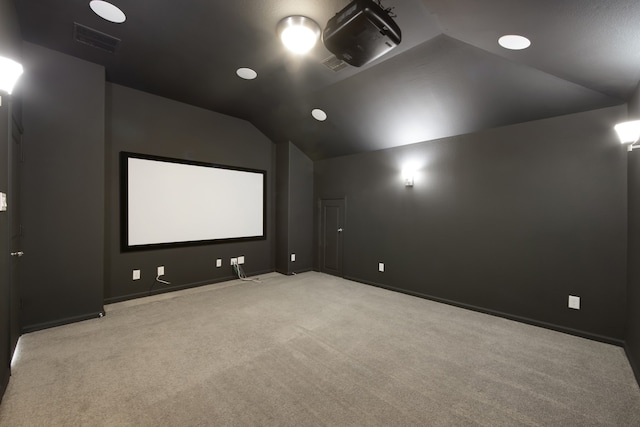 carpeted cinema room featuring vaulted ceiling