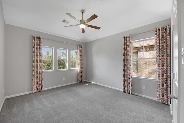 empty room with carpet floors, ceiling fan, and a healthy amount of sunlight