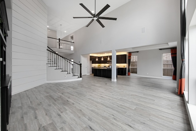 unfurnished living room with ceiling fan, light hardwood / wood-style flooring, and high vaulted ceiling