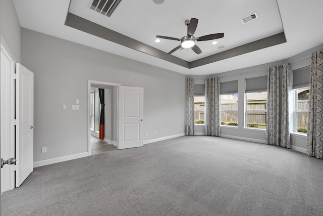 carpeted empty room featuring a tray ceiling and ceiling fan