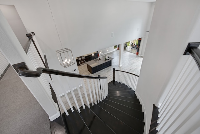 staircase featuring carpet flooring, a high ceiling, and an inviting chandelier