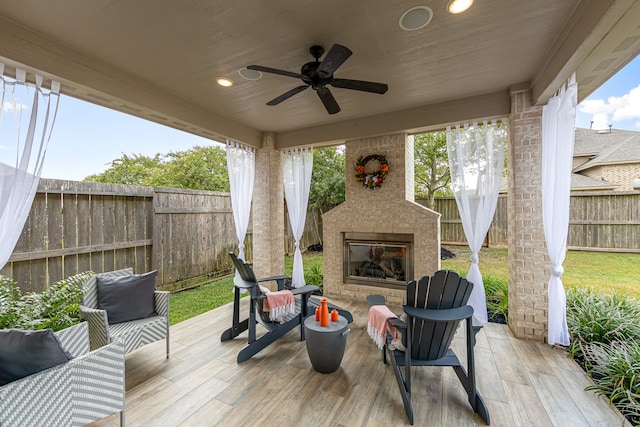 deck featuring ceiling fan and an outdoor brick fireplace