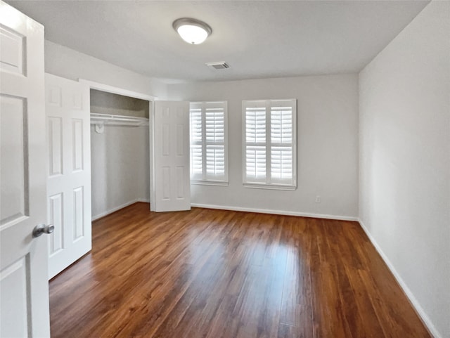 unfurnished bedroom with dark wood-type flooring and a closet