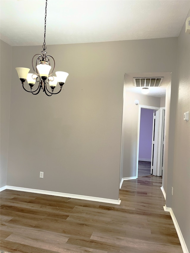 unfurnished dining area with an inviting chandelier and light wood-type flooring