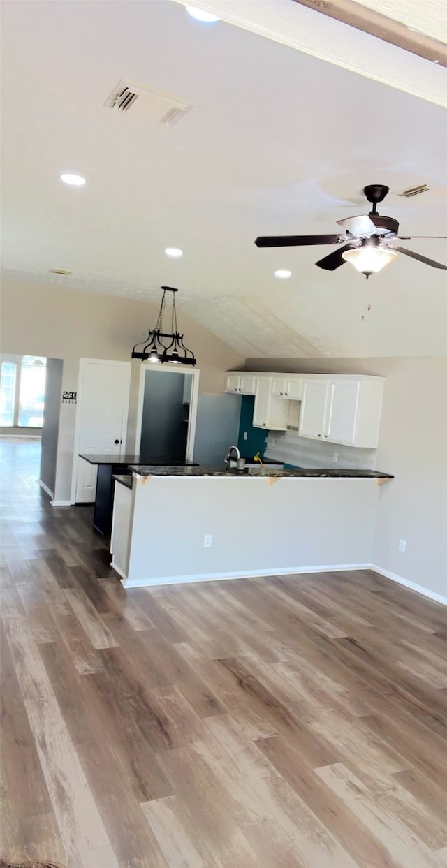 kitchen featuring white cabinetry, wood-type flooring, and vaulted ceiling