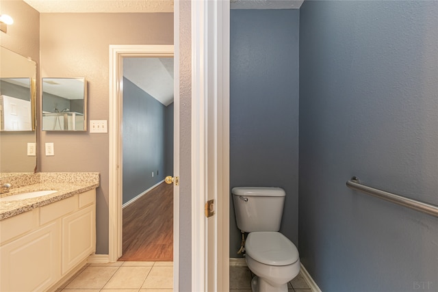 bathroom with toilet, a textured ceiling, vanity, and tile patterned floors