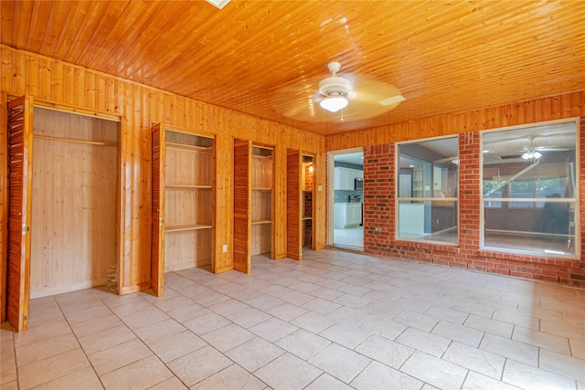 unfurnished bedroom featuring wood ceiling, light tile patterned floors, wooden walls, and ceiling fan