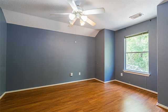 empty room featuring hardwood / wood-style floors, vaulted ceiling, a textured ceiling, and ceiling fan