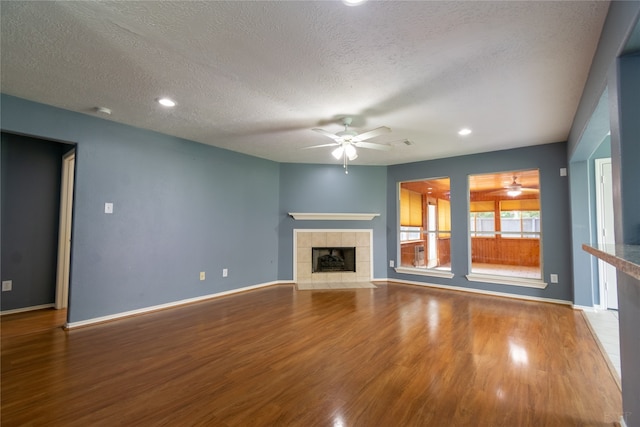 unfurnished living room featuring ceiling fan, a textured ceiling, a fireplace, and hardwood / wood-style floors