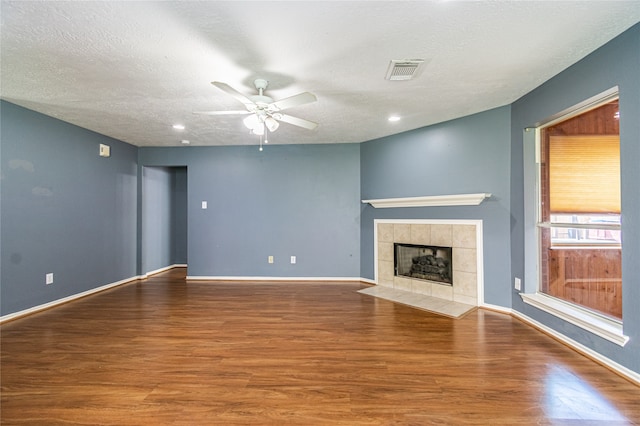 unfurnished living room with a textured ceiling, hardwood / wood-style flooring, a fireplace, and ceiling fan