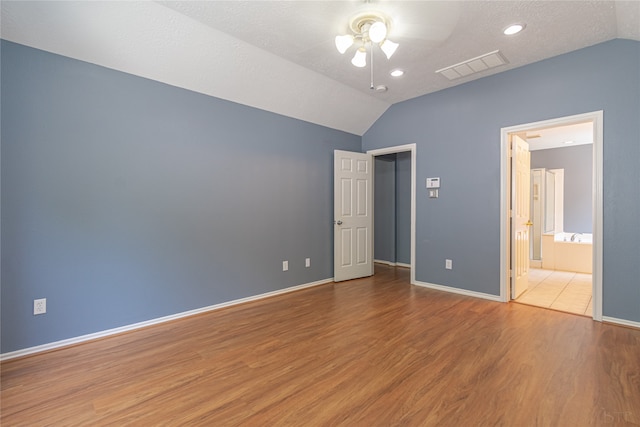 unfurnished bedroom featuring connected bathroom, ceiling fan, lofted ceiling, and hardwood / wood-style floors