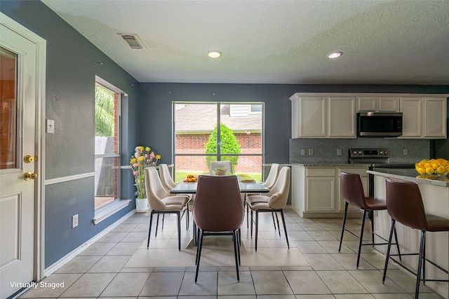 tiled dining room with a textured ceiling