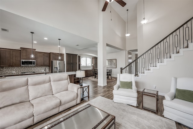 living room with dark hardwood / wood-style flooring, high vaulted ceiling, and ceiling fan