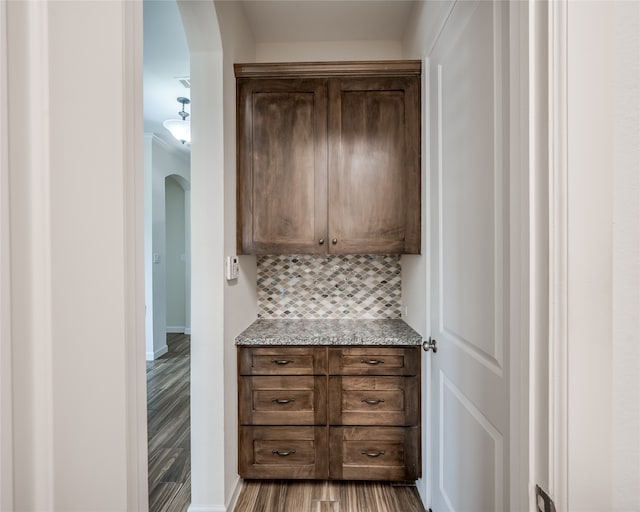 interior space featuring wood-type flooring, light stone countertops, and decorative backsplash