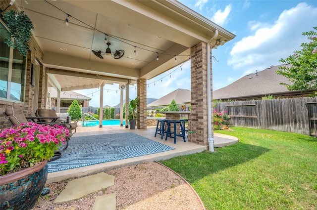 view of patio featuring ceiling fan, a fenced in pool, and a bar