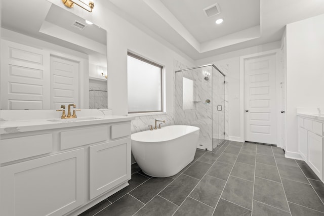 bathroom featuring vanity, separate shower and tub, a tray ceiling, and tile patterned flooring