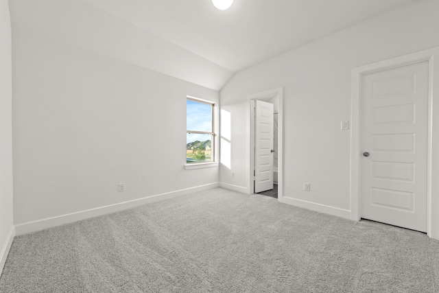 unfurnished bedroom with light colored carpet and vaulted ceiling