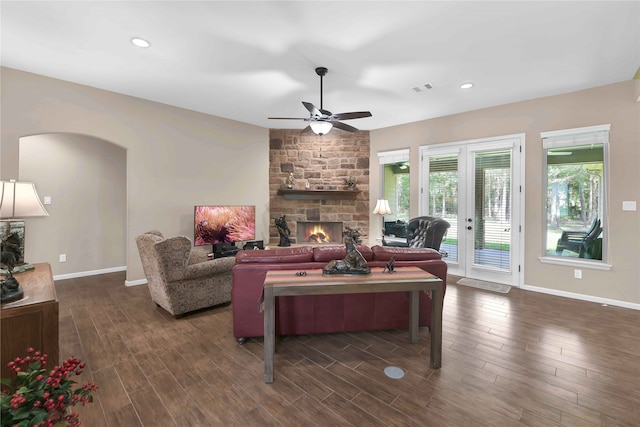 living room with ceiling fan, dark hardwood / wood-style floors, and a stone fireplace