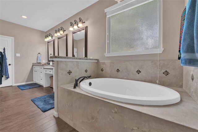 bathroom with a tub, hardwood / wood-style flooring, and vanity