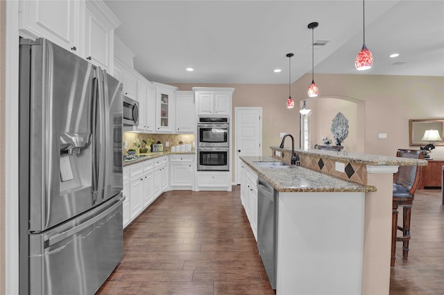 kitchen with light stone countertops, stainless steel appliances, sink, dark hardwood / wood-style floors, and a kitchen bar