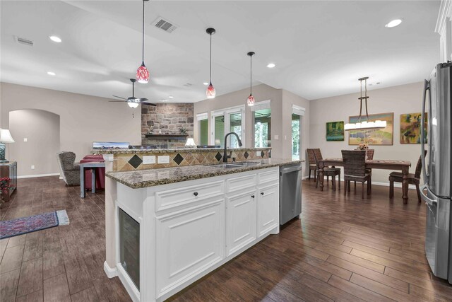 kitchen with a fireplace, white cabinets, stainless steel appliances, and ceiling fan