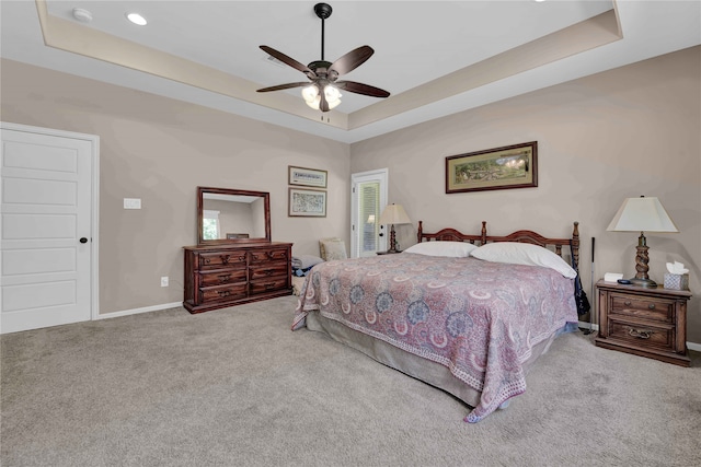 carpeted bedroom with a tray ceiling and ceiling fan